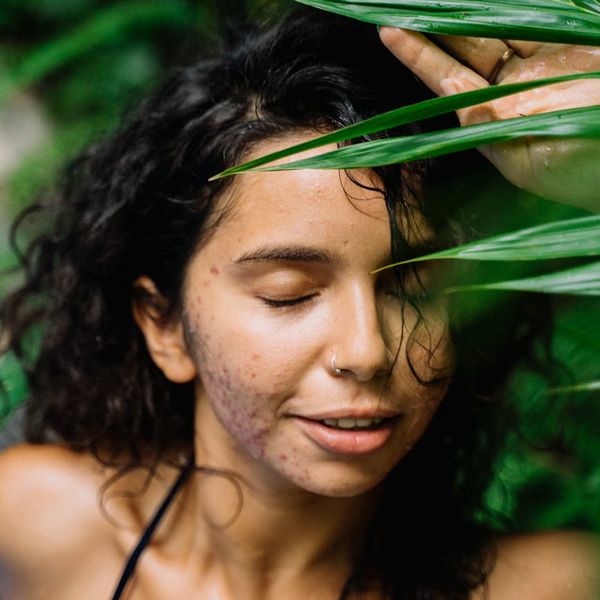 Person smiling peacefully with eyes closed in a calm, green-tinted environment.